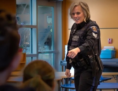 photo showing a female police officer speaking to a number of young children in school